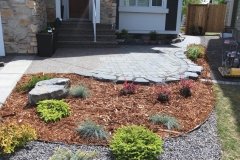 Mulch and rock beds separated with black edging with assorted perennials and shrubs