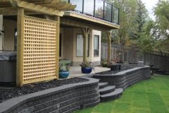 retaining wall - stacked armour stone with black mulch beds and pressure treated privacy screen and pergola