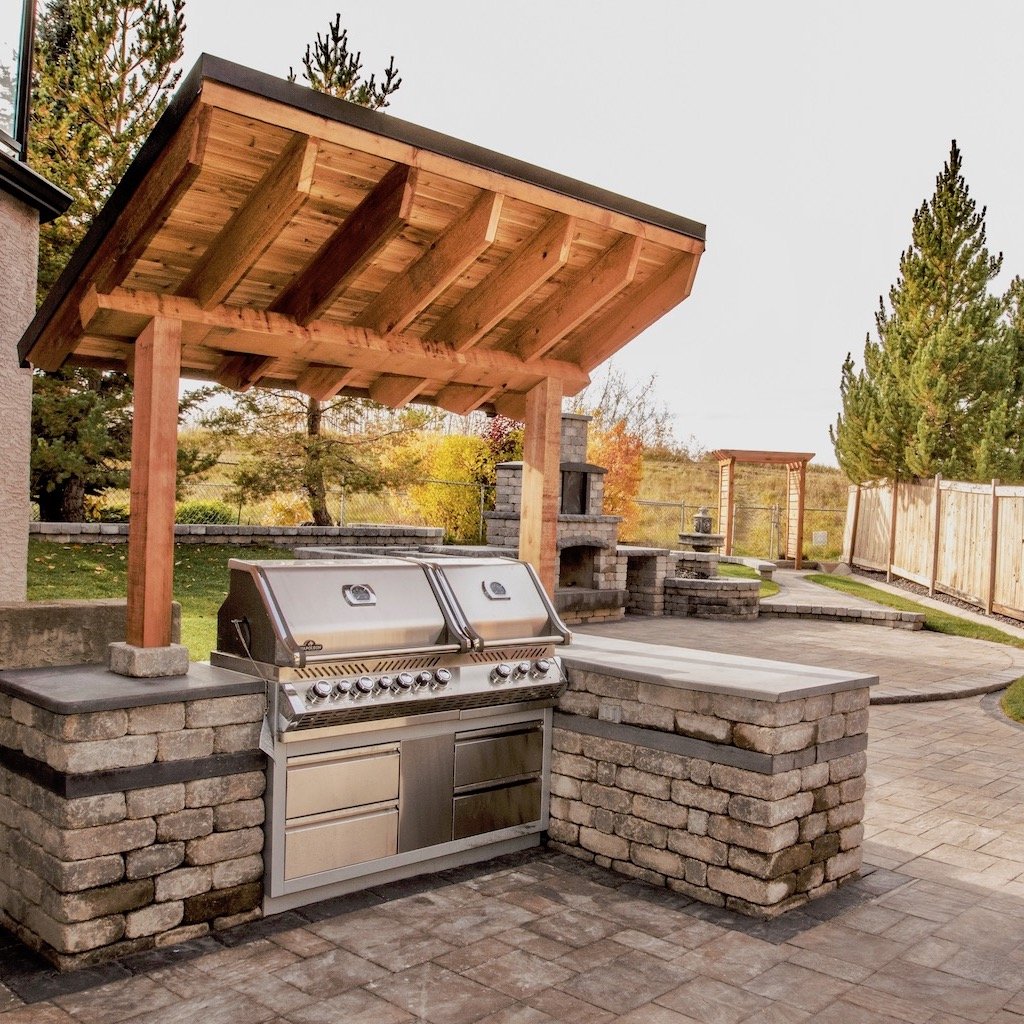 outdoor kitchen with a bbq and fireplace built with paving stones