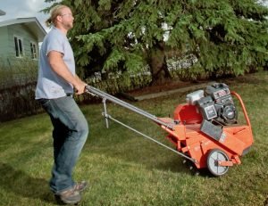 man aerating front lawn with a core aeration machine