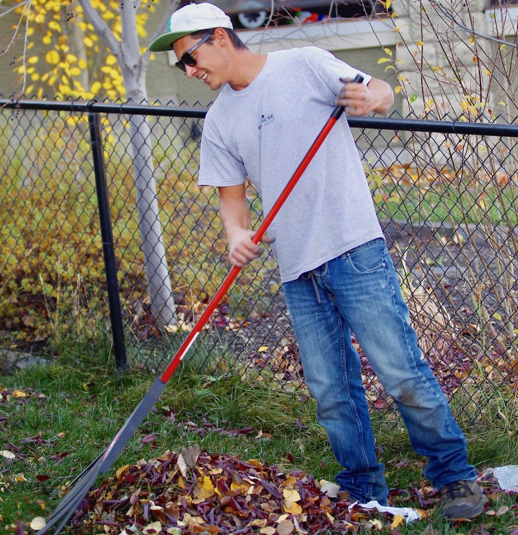 young man raking leaves into a pile