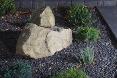 Borders - Charcoal pisa II retaining wall and revers a cap capstone, with rundle ground cover and assorted perennials.