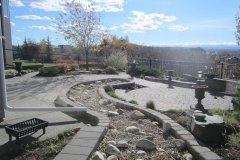 Borders - stackstone dry wall around dry river bed with cobble stone patio surrounding
