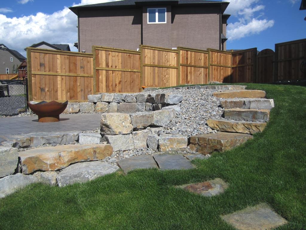 retaining wall - stackable ironstone slab retaining wall and steps with charcoal holland pavers and washed gravel beds