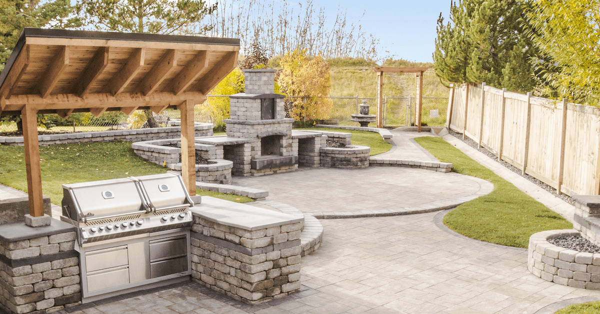 backyard landscape with paving stone patio outdoor kitchen and fireplace